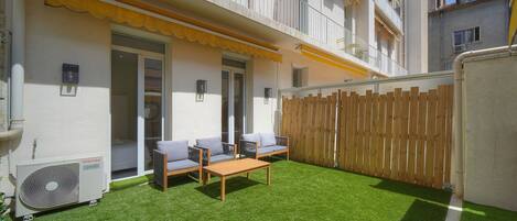 A residential building with a balcony, a wooden fence, and a small patio with furniture.