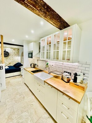 A modern kitchen with white cabinets, a stone wall, a wooden ceiling, and a built-in oven. - 15398910 FRGK Private Townhouse HQ Walk to Palais (Cannes)