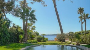A pool with a clear view of the sea, surrounded by greenery and tall trees. - FRGK Villa Mare Moure Rouge Palm Beach (Cannes)