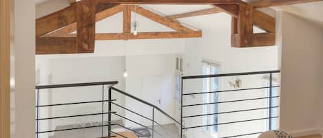 A staircase with a wooden ceiling and metal railings leading to an upper floor.