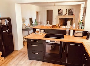 Eine moderne Küche mit Holzarbeitsplatte, schwarzen Schränken, einem eingebauten Backofen und einer Kaffeemaschine.