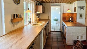 Eine Küche mit Holzarbeitsplatten, einer Pendelleuchte und einem gefliesten Boden.