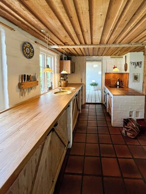A kitchen with wooden countertops, a hanging light fixture, and a tiled floor. - Artist's house in first row by Smålandshavet (Horslunde)