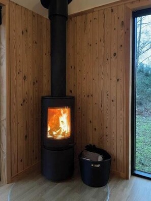 Ein Kaminofen in einer Ecke, mit Holzwänden und einem Fenster.