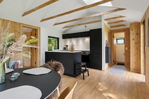 Eine moderne Küche mit Holzbalken, einem Essbereich mit rundem Tisch und Blick ins Freie.
