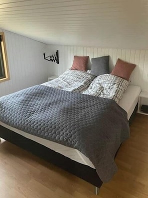 Ein Bett mit gesteppter Bettdecke, ein Nachttisch und eine Wandleuchte.