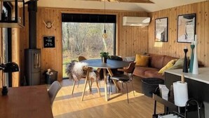 A cozy cabin interior with a dining table, chairs, a sofa, and a kitchen area. - Newly renovated holiday home near Torndal beach (Hals)