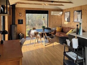 Ein gemütliches Blockhaus-Interieur mit Esstisch, Stühlen, einer Couch und einer Küchenzeile.