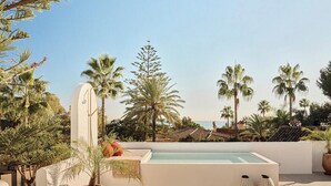 A rooftop pool with a view of palm trees and a distant coastline. - Villa with rooftop terrace near beach in Marbella (Marbella)