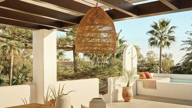 An outdoor dining area with a wooden table, wicker chairs, and a hanging rattan light fixture. - Villa with rooftop terrace near beach in Marbella (Marbella)