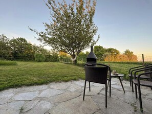 A patio area with a swing set, a wicker chair, and a small table with a pot. - Authentic farm close to the water on Samsø (Samsø)