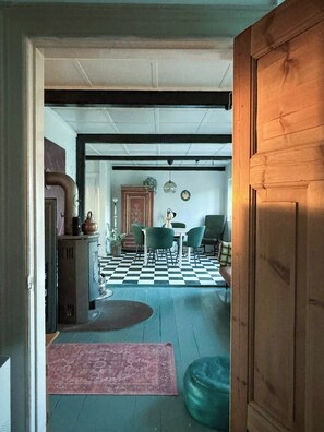 A room with a checkered floor, a dining table with chairs, a wooden door, and a radiator. - Authentic farm close to the water on Samsø (Samsø)