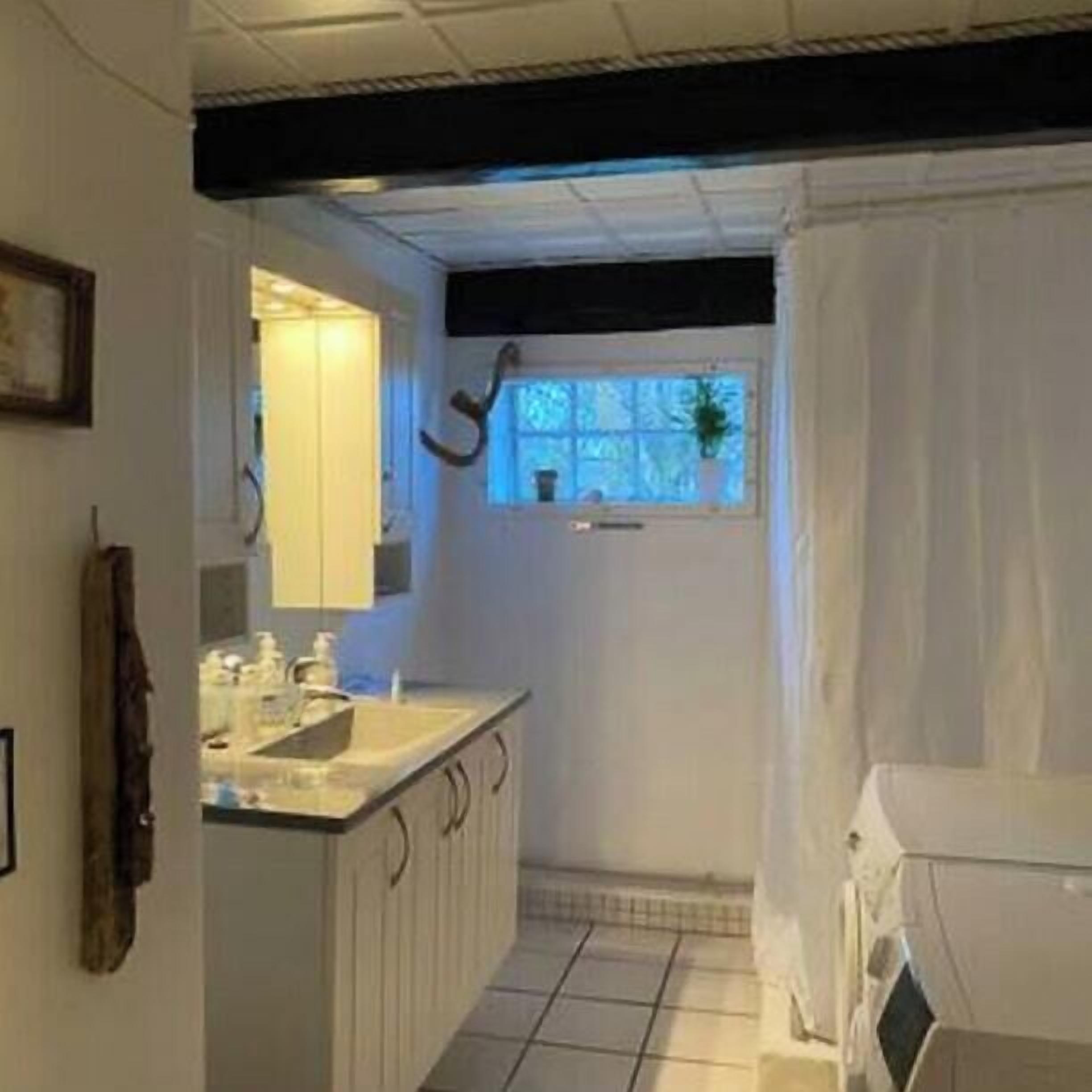 Un bany petit i funcional, amb un lavabo, mirall i finestra.
