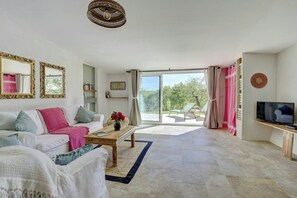 Ein geräumiges Wohnzimmer mit Sofa, Couchtisch und Fernseher.