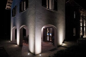 A building with a modern architectural style, featuring arched doorways and a well-lit entrance. - Stone house in Piedmont with infinity pool (Cossano Belbo)