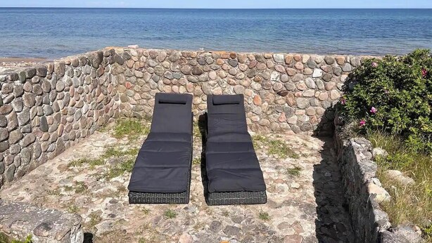 A stone wall with two black sun loungers facing the sea. - Enjoy the sound of crashing waves and ocean views (Græsted)