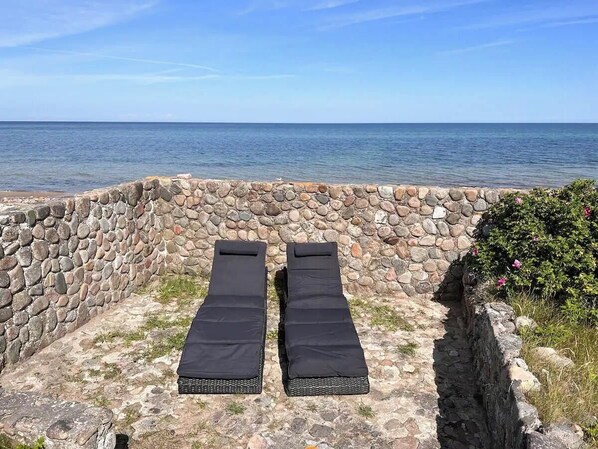 A stone wall with two black sun loungers facing the sea. - Enjoy the sound of crashing waves and ocean views (Græsted)