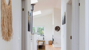 A hallway with wooden flooring, white walls, and a ceiling light fixture. - Enjoy the sound of crashing waves and ocean views (Græsted)