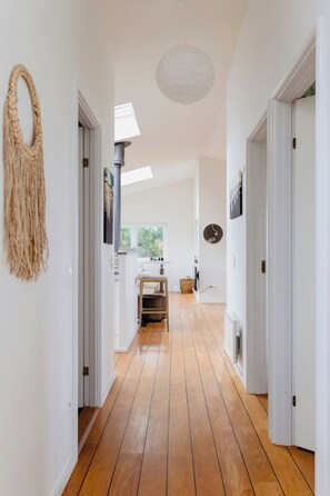 A hallway with wooden flooring, white walls, and a ceiling light fixture. - Enjoy the sound of crashing waves and ocean views (Græsted)