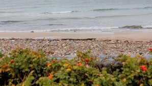 A beach with pebbles and bushes in the foreground. - Enjoy the sound of crashing waves and ocean views (Græsted)