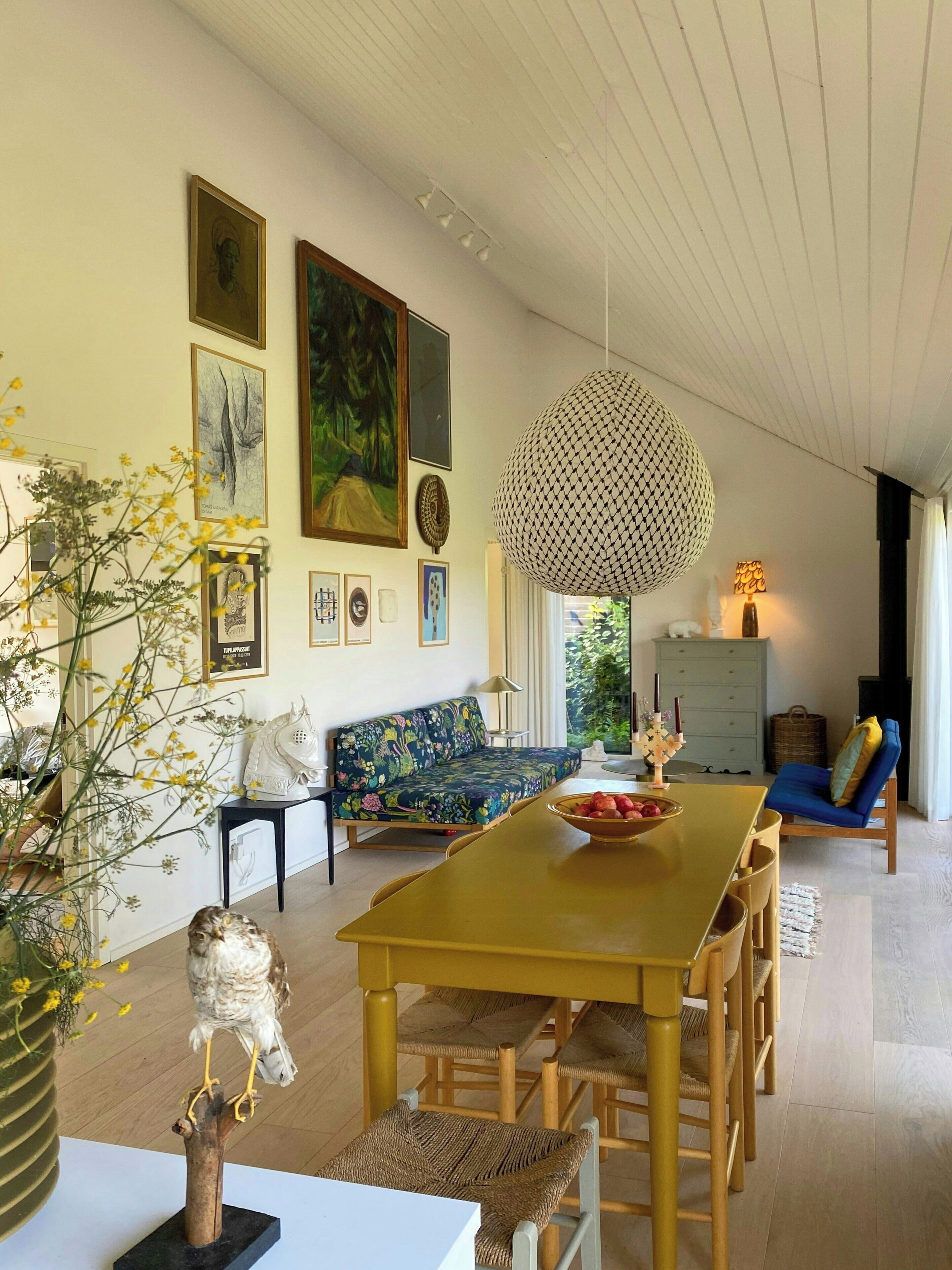 A dining area with a wooden table and chairs, a sofa, and wall art.