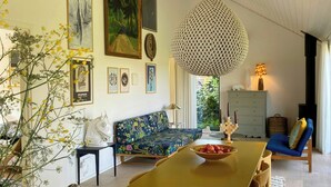 A dining area with a wooden table and chairs, a sofa, and wall art. - Artistic holiday home near Tisvilde Hegn (Vejby)