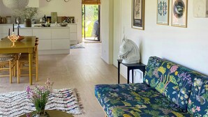 A spacious living area with a sofa, a dining table, and a kitchen in the background. - Artistic holiday home near Tisvilde Hegn (Vejby)