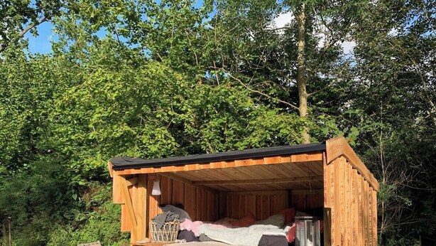 A wooden cabin with a bed, a small table, and a kettle. - Colourful summerhouse close to Vig (Vig)
