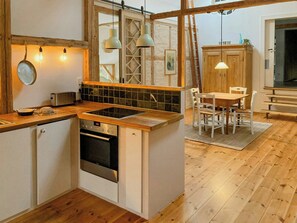 Une cuisine équipée d’une cuisinière intégrée, un coin repas avec une table et des chaises, et un plancher en bois.
