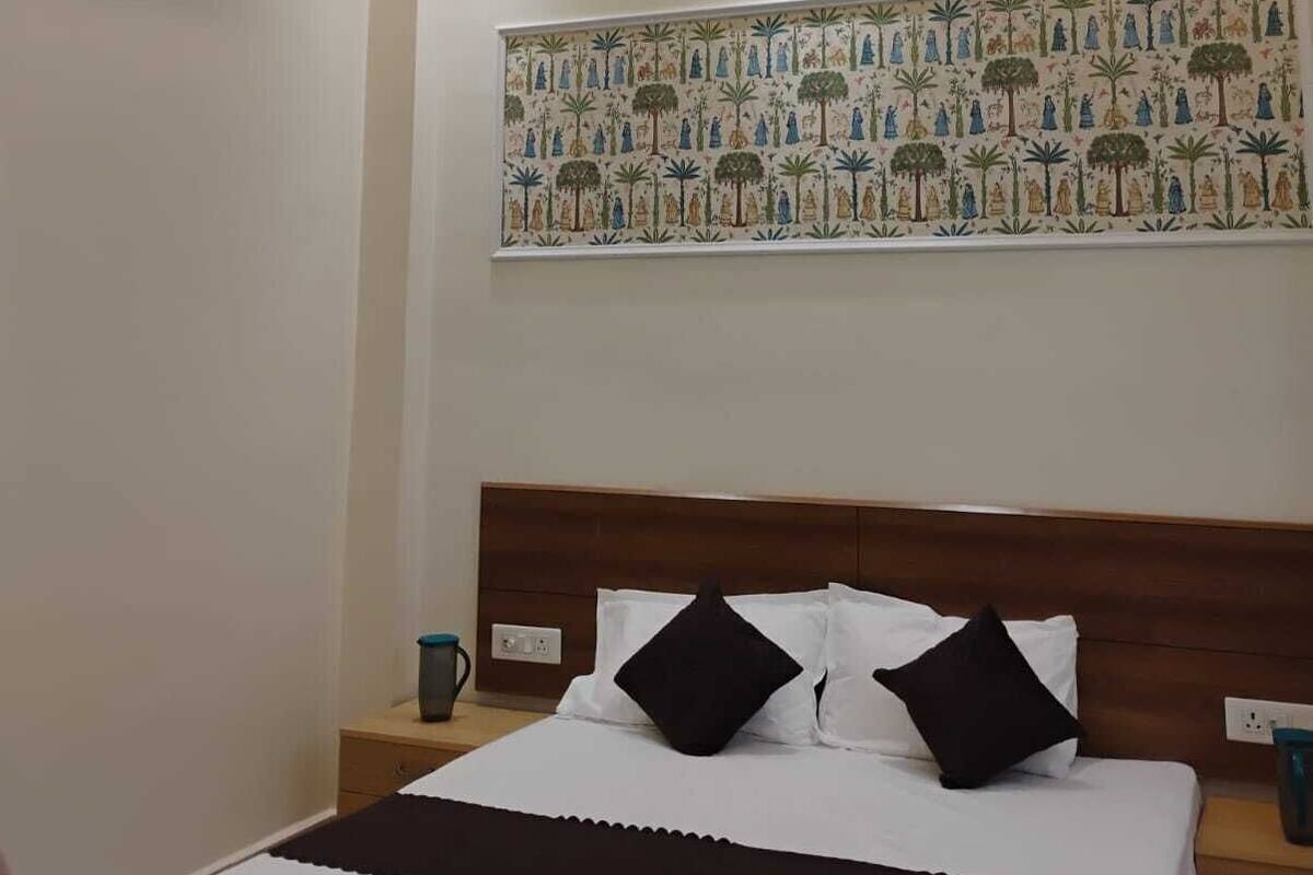 Un dormitorio con cama, ventilador de techo, aire acondicionado y un gran cuadro decorativo.