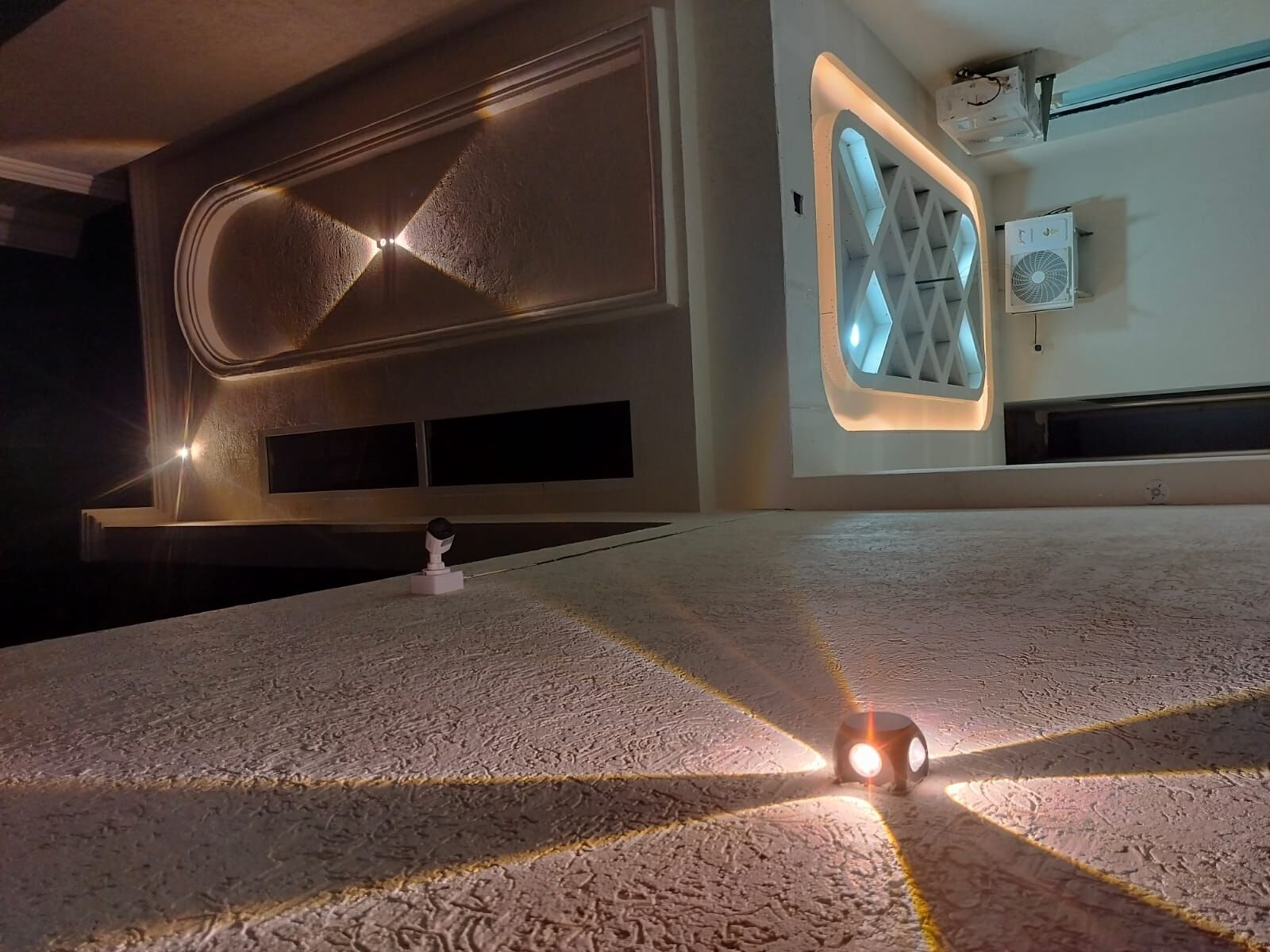Un interior moderno con un diseño de techo único, un equipo de aire acondicionado instalado en la pared y un robot en el suelo.