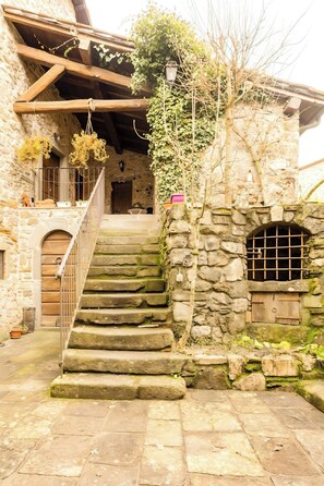 A stone staircase leading to a wooden door, surrounded by greenery and stone walls. - Nature retreat in Garfagnana (San Romano in Garfagnana)