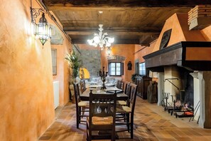 A dining area with a wooden table, chairs, a chandelier, and a fireplace. - Nature retreat in Garfagnana (San Romano in Garfagnana)