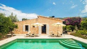 Une villa en pierre dotée d’une piscine, d’un espace salon extérieur et d’un jardin.