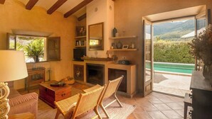 Un salon doté d’une cheminée, d’un coin repas et offrant une vue sur un paysage verdoyant grâce à une porte ouverte.