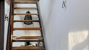 En trætrap med gelænder, en hængende lampe og en vægmonteret knage.