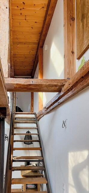 A wooden staircase with a metal railing, a hanging light fixture, and a wall-mounted hook. - Modernity in farmhouse with lagoon view (Ummanz)