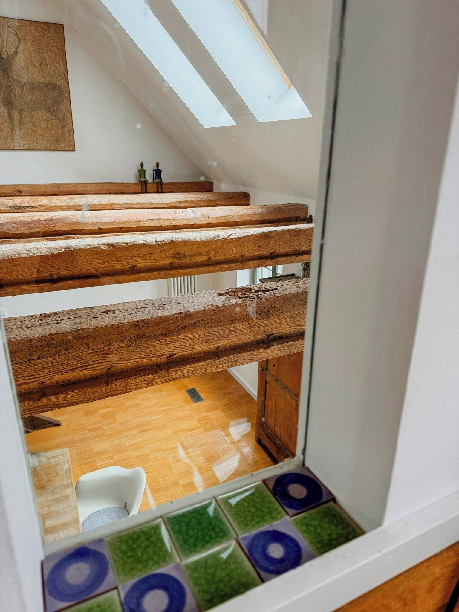 A multi-level wooden staircase with a skylight, a tiled floor, and a white chair.