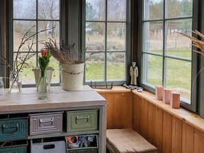 A room with a wooden bench, a window seat, a small statue, and storage drawers. - Modernity in farmhouse with lagoon view (Ummanz)