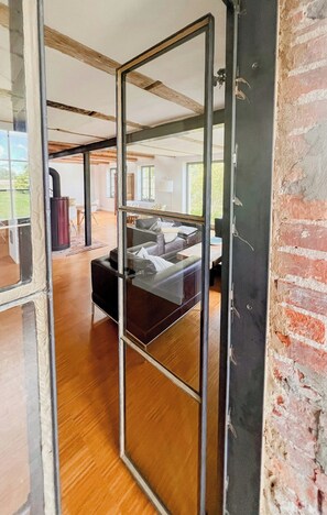A room with a glass partition, a bed, a fireplace, and a view of the outdoors. - Modernity in farmhouse with lagoon view (Ummanz)