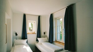 Een kamer met twee eenpersoonsbedden, een raam en een deur.