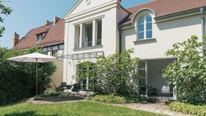 Een huis met twee verdiepingen, een overdekte patio, een kleine tuin en een zichtbare garage.