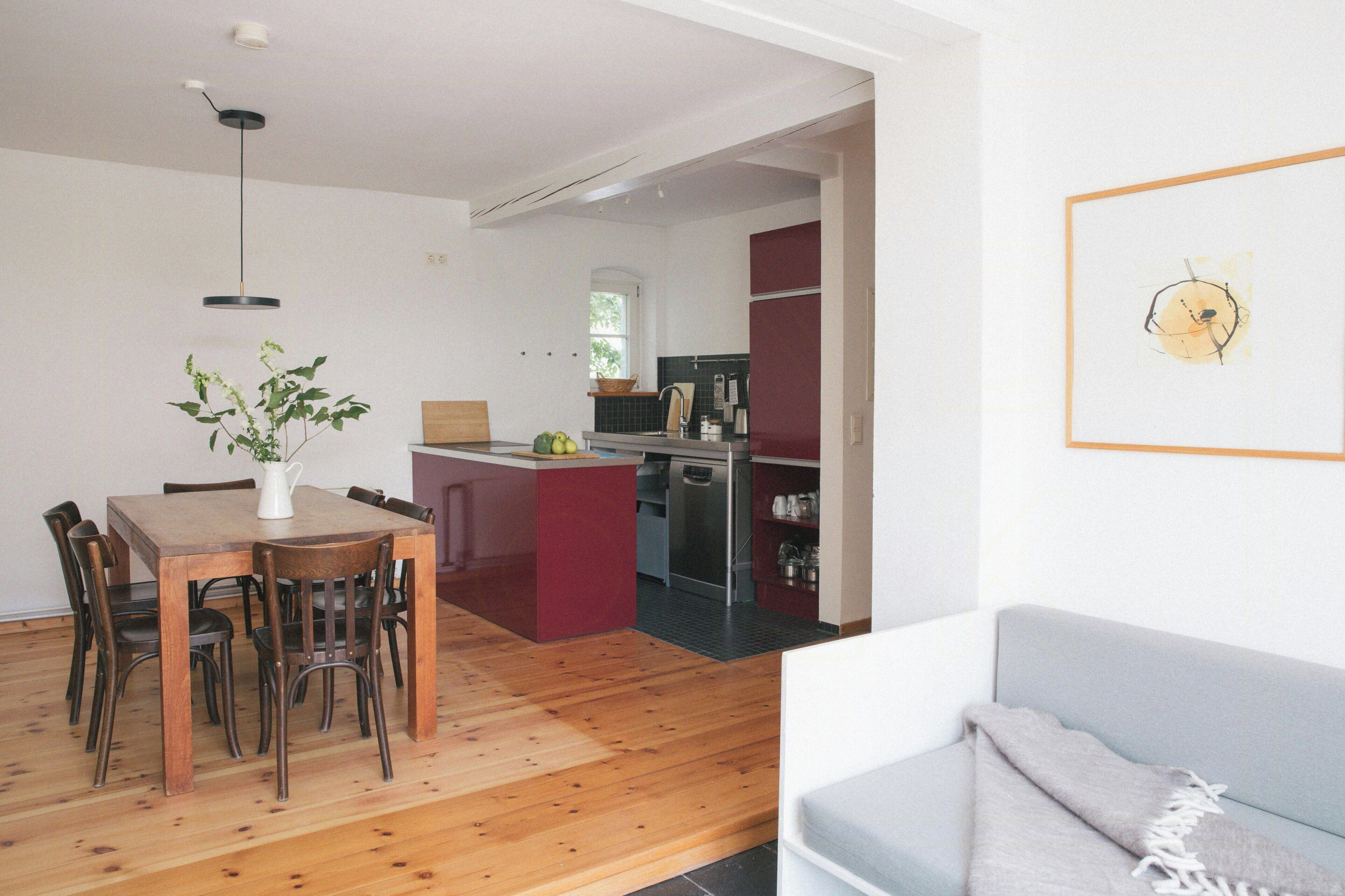 Eine moderne Küche mit Essbereich, Holzboden und einem grauen Sofa.