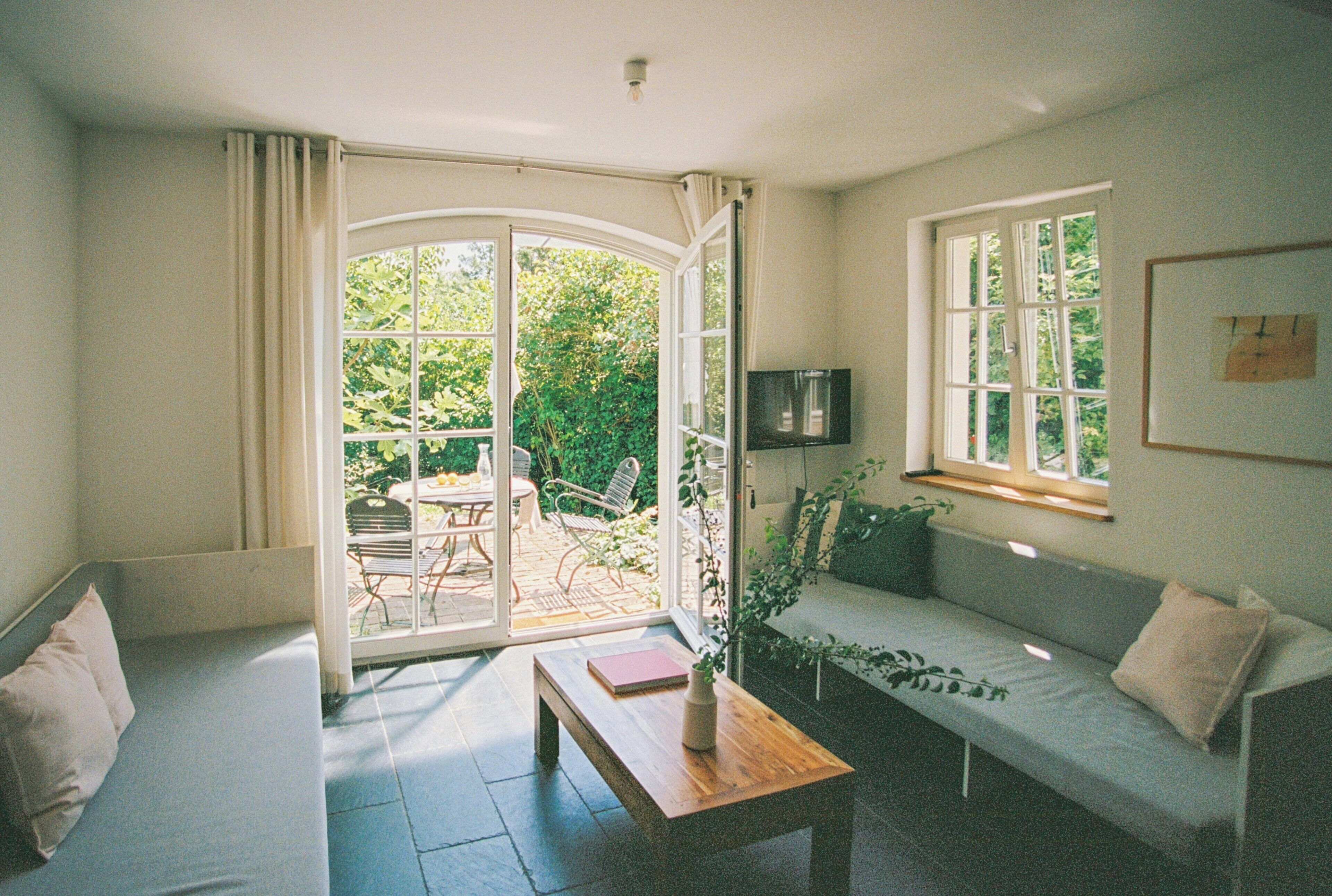 Ein Zimmer mit einer Couch, einem Tisch, einer Bank, einem Fernseher und einem Fenster.