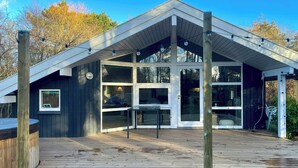 A modern building with large windows, a wooden deck, and a covered outdoor area. - Cottage with beach access on Sjællands Odde (Sjællands Odde)