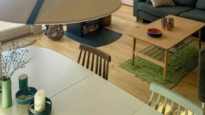 A modern interior with a dining area, a sofa, and a large window. - Cottage with beach access on Sjællands Odde (Sjællands Odde)