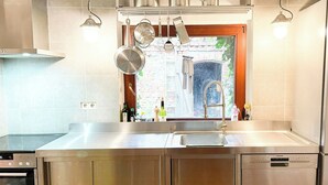 A kitchen with stainless steel appliances, a window with a view, and hanging pots.