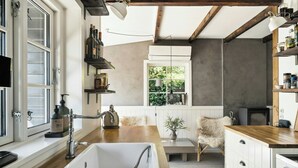 A kitchen with a wooden countertop, white cabinets, a built-in sink, and a window with a view of greenery. - Modern summer house near Udsholt Beach (Græsted)