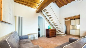 Un amplio espacio de sala con una escalera, un conjunto de sofás, una mesita y un armario.