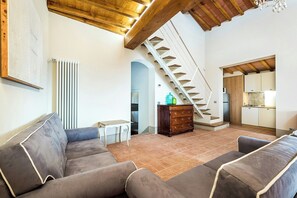 A spacious living area with a staircase, a sofa set, a small table, and a cabinet. - Apartment with pool and views of Valdarno (Reggello)
